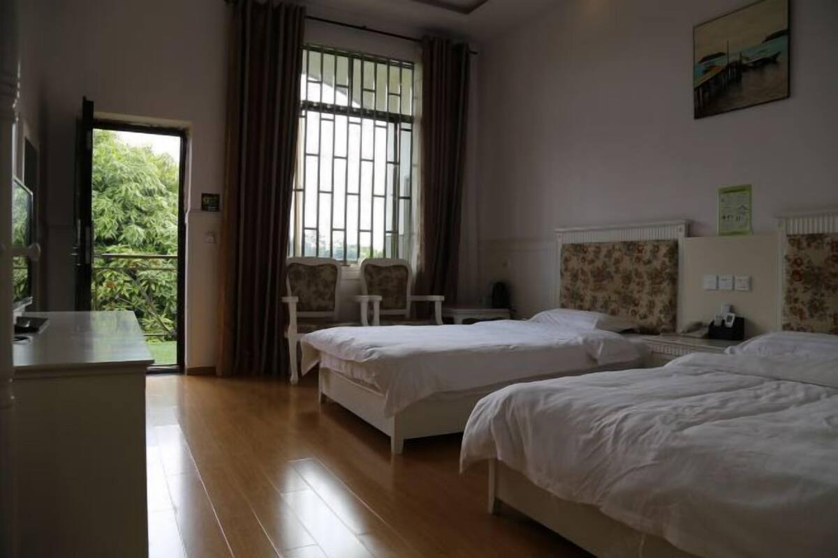 A hotel room with two beds, a desk, a chair, and a window with curtains.