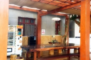 Un interior en estilo japonés tradicional con una mesa de madera, una máquina expendedora y un cartel que indica prohibido fumar.