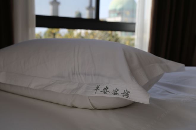 A bed with a white pillow and a piece of paper with Chinese characters on it.