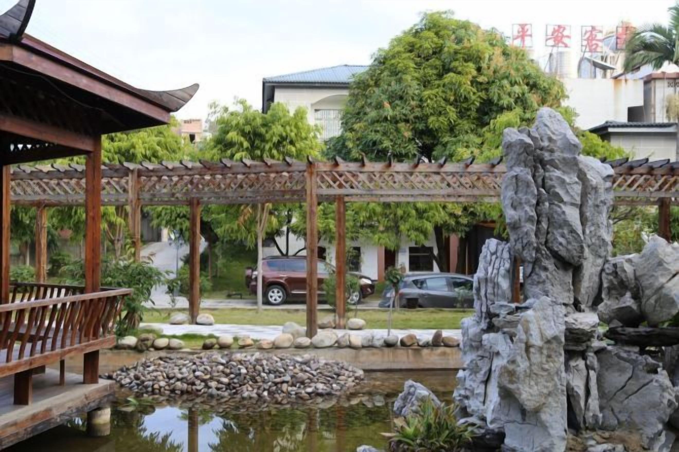 A traditional pavilion with a wooden roof, a rock garden, and a pond.