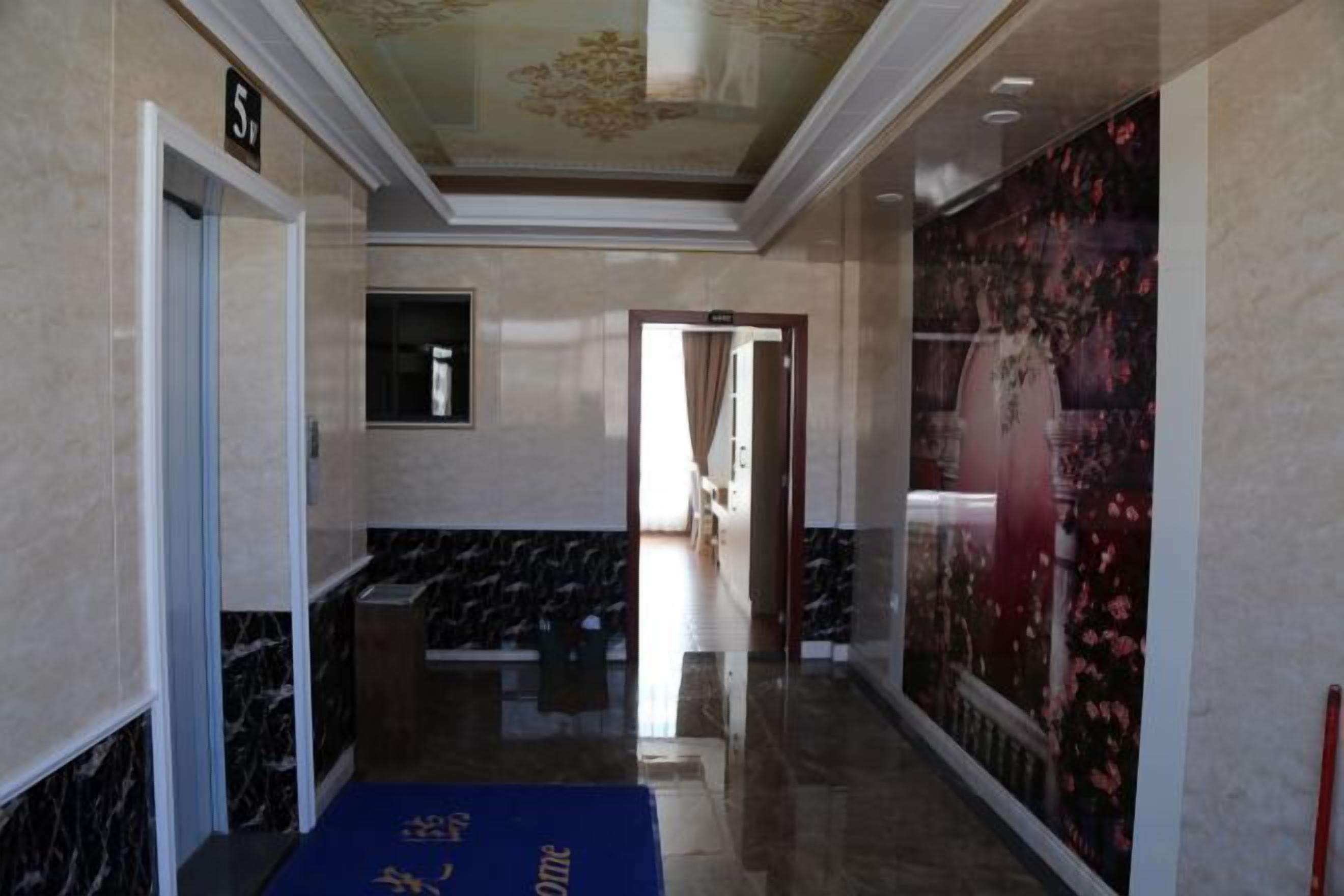 A hallway with marble walls, a blue carpet, and a door marked with the number 5.