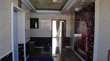 A hallway with marble walls, a blue carpet, and a door marked with the number 5.