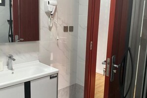 Un baño con lavamanos blanco, secador de pelo y puerta roja.
