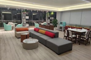 Un área de estar moderna con un sofá modular, una mesa de centro redonda y un juego de comedor.