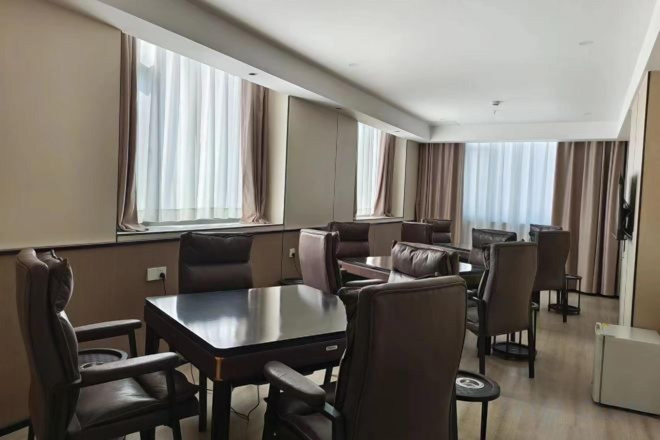 A hotel room with a dining area, a large window with curtains, and a flat-screen TV.