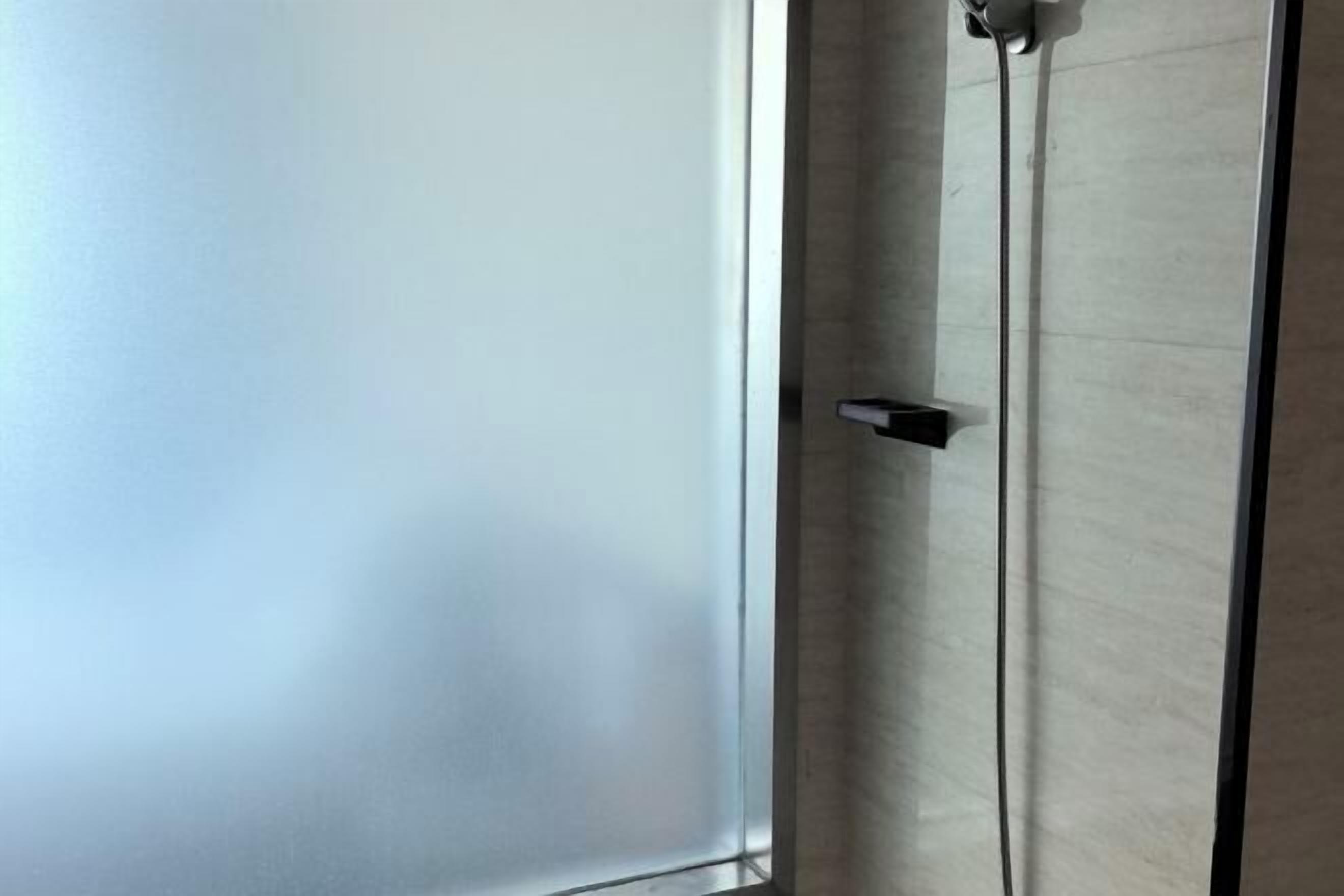 A room with a large window, a door with a handle, and a visible wall.