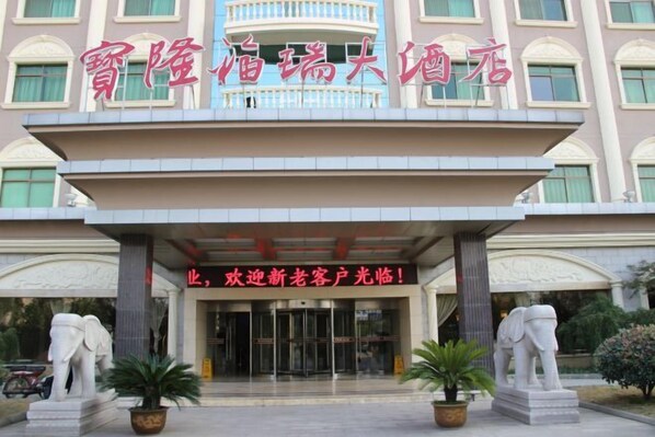 A hotel entrance with a large sign, two elephant statues, and a modern facade. - Baolong Furui Hotel (Changzhou)