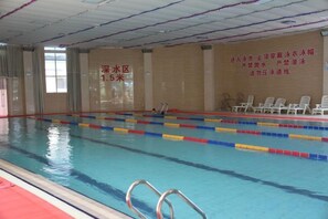 Una piscina interior con separadores de carril, un bloque de salida y una pared con texto.