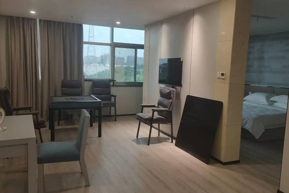 Quarto de hotel com cama, escrivaninha, cadeira, televisão e janela com vista para a cidade.