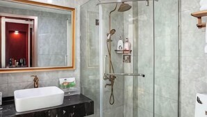 Casa de banho com cabine de duche em vidro, lavatório branco e espelho com moldura de madeira.