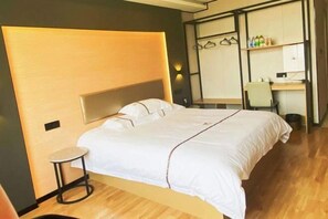 A hotel room with a bed, a small round table, a desk, and a wardrobe.