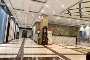 Un vestíbulo de hotel con mostrador de recepción y un elemento decorativo en la pared.