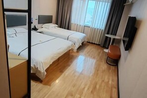 A hotel room with two beds, a bedside table, a chair, a small table, and a window with curtains. - Wanjia Zhenxuan Hotel (long distance bus station) (Tengzhou)