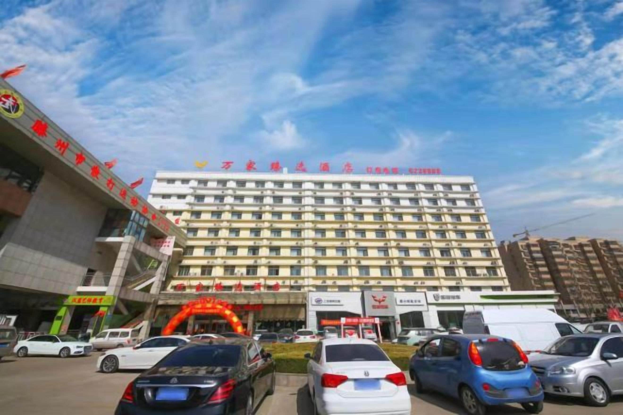 Un hôtel à plusieurs étages, un parking et un ciel dégagé.