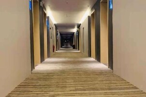Pasillo de hotel con piso alfombrado, puertas a ambos lados e iluminación en el techo.