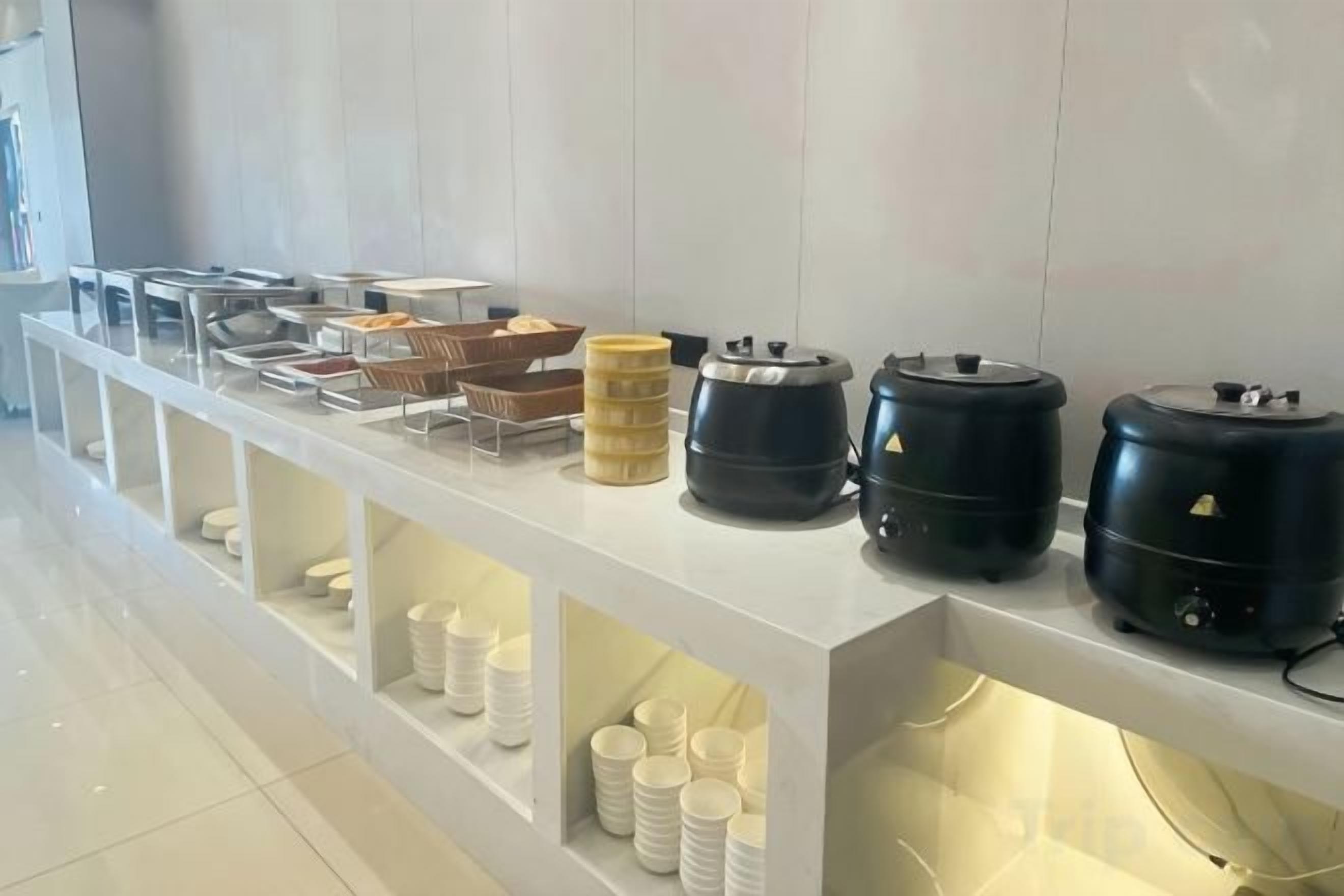 A buffet setup with various food containers and serving utensils.