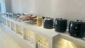 A buffet setup with various food containers and serving utensils.