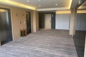 A hotel corridor with carpeted flooring, wooden paneling, and a door at the end. - Wanjia Zhenxuan Hotel (long distance bus station) (Tengzhou)