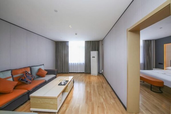 A modern hotel room with a sofa, a coffee table, a bed, and a desk. - Wanjia Zhenxuan Hotel (long distance bus station) (Tengzhou)
