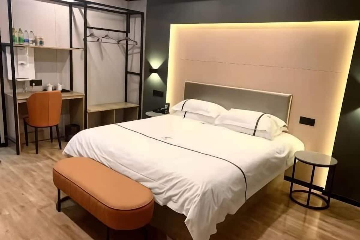 A modern hotel room with a large bed, a desk, and a chair.
