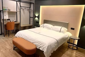 A modern hotel room with a large bed, a desk, and a chair. - Wanjia Zhenxuan Hotel (long distance bus station) (Tengzhou)