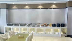 Un espace buffet pour le petit-déjeuner proposant une variété d’aliments et disposant de tables et de chaises.