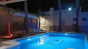 Ein Swimmingpool mit Delfin-Motiv, umgeben von Palmen und einer Liege.