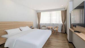 A hotel room with a large bed, a desk with a TV, a chair, and a small table. - Jiada Hotel (Zhuhai Lovers Road Seaside Swimming Pool) (Zhuhai)