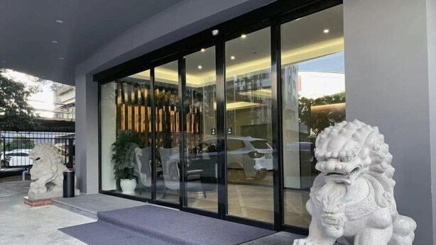 A building entrance with a glass door, a stone lion statue, and a potted plant. - Jiada Hotel (Zhuhai Lovers Road Seaside Swimming Pool) (Zhuhai)