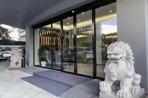 A building entrance with a glass door, a stone lion statue, and a potted plant. - Jiada Hotel (Zhuhai Lovers Road Seaside Swimming Pool) (Zhuhai)