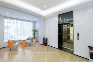 Eine moderne Lobby mit einer Rezeption, einer Sitzecke und einem Aufzug.