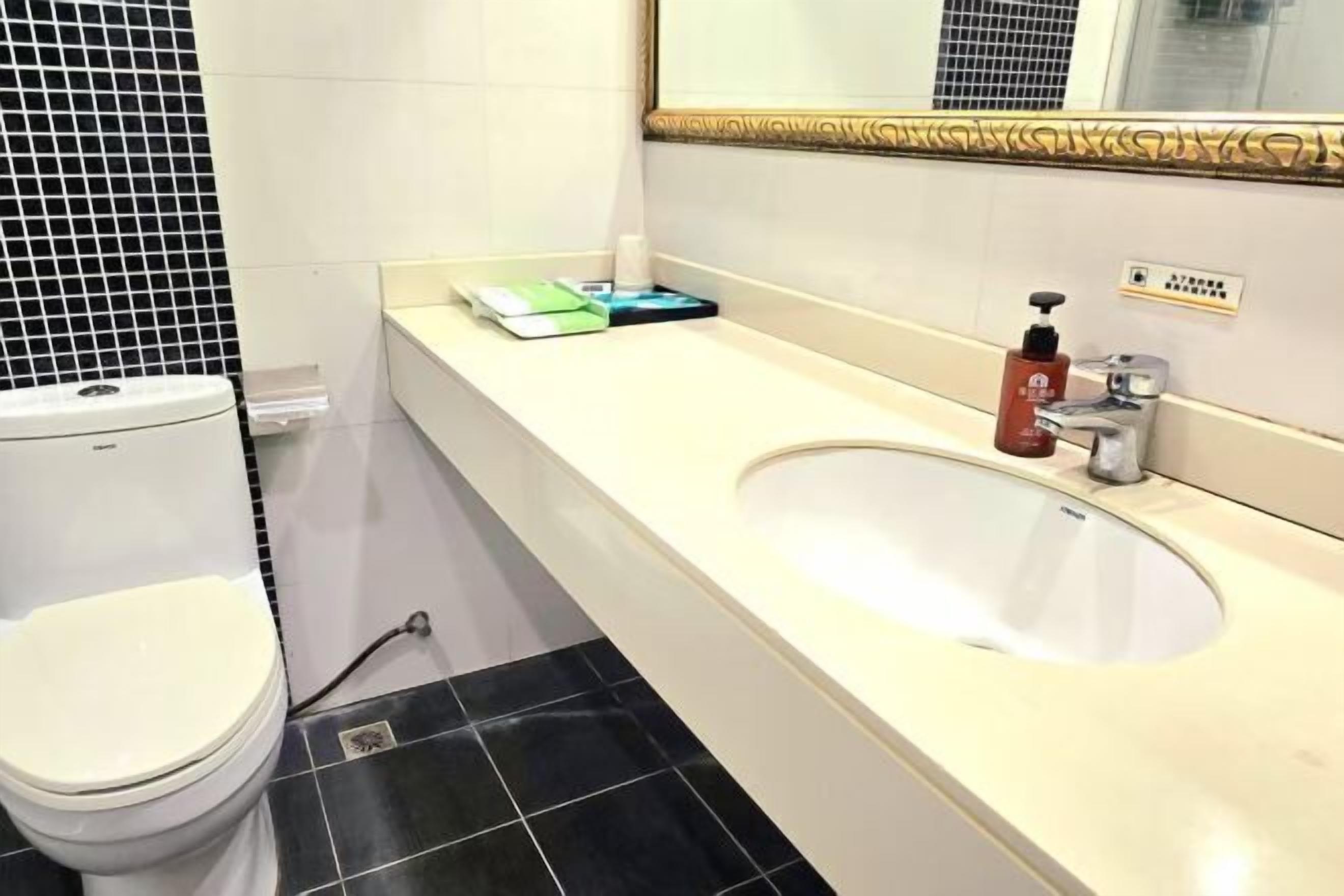 A bathroom with a white toilet, a sink with a mirror above it, and a black tiled floor.