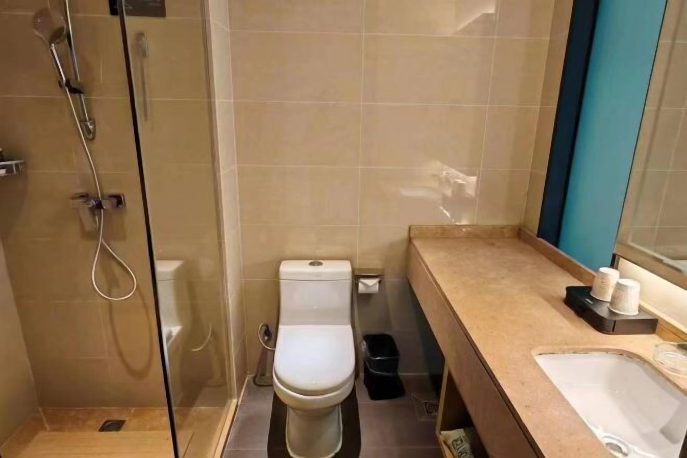 Un baño con ducha separada por mampara de vidrio, inodoro, lavabo y espejo.