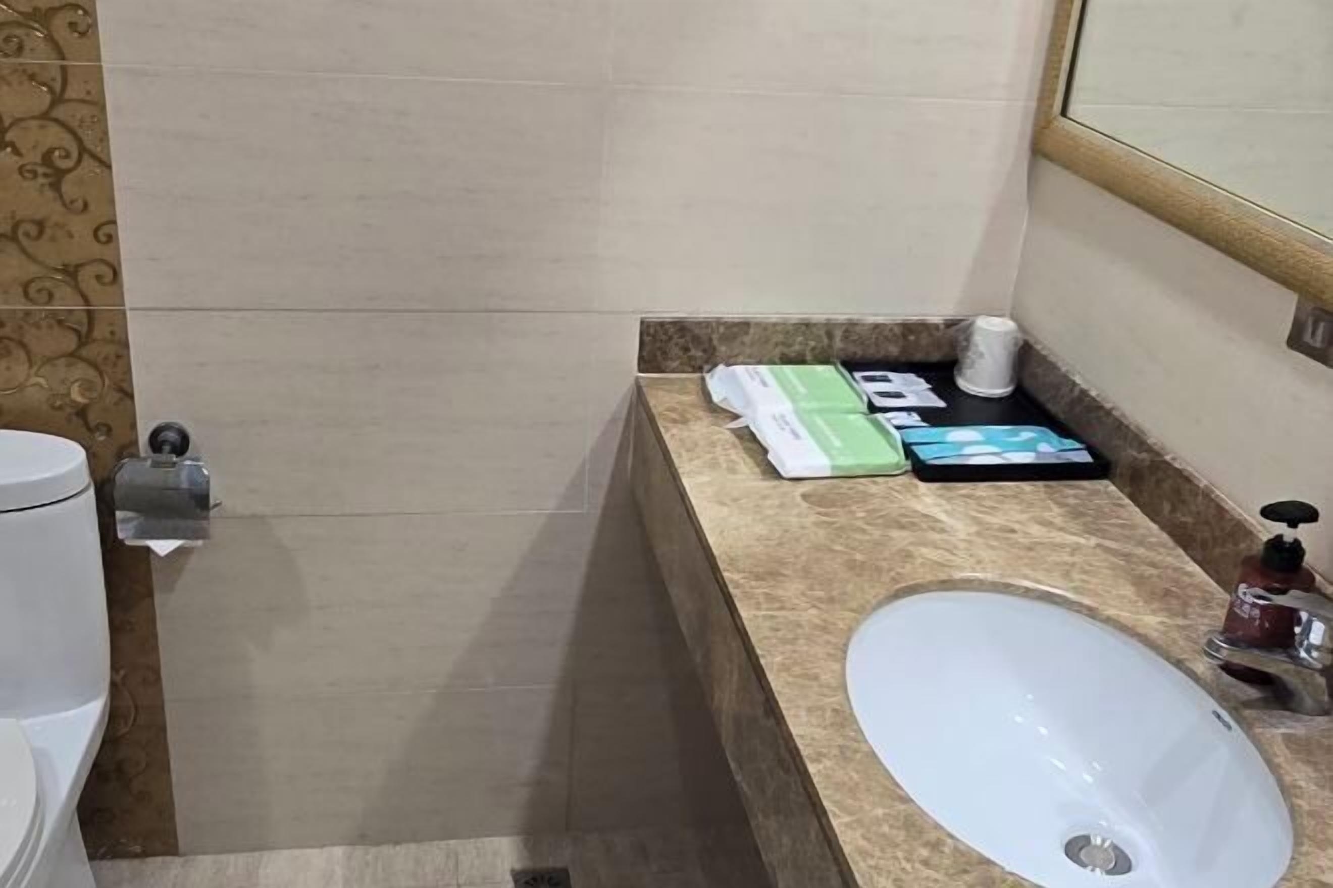 A bathroom with a white sink, a toilet, and a towel dispenser.