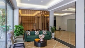 A modern lobby with a green sofa, a round coffee table, and a large potted plant. - Jiada Hotel (Zhuhai Lovers Road Seaside Swimming Pool) (Zhuhai)