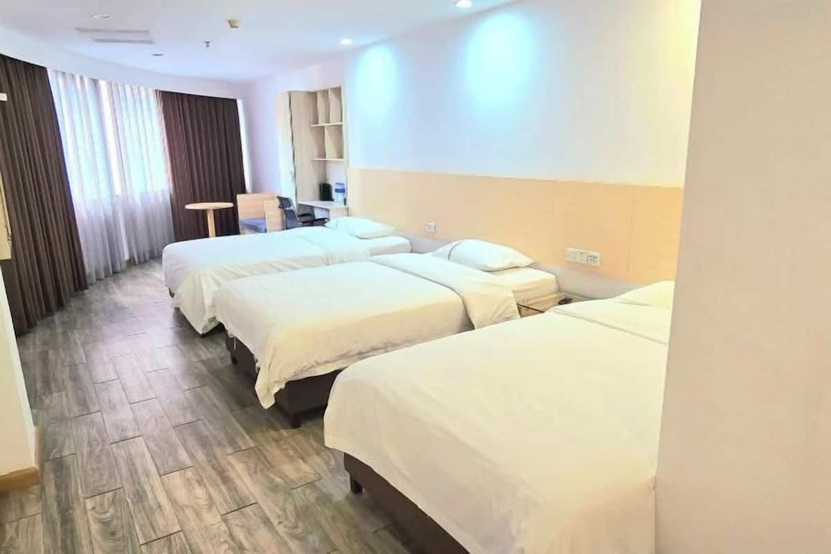 A hotel room with three beds, a desk, and a chair.