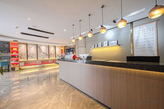 Zona de recepción de hotel con suelo de mármol, mostrador de recepción y una pared decorada con cuadros.