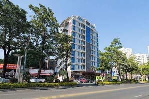 A multi-story hotel with a modern facade, located on a street with parked cars and trees. - The Sussie Hotel (Quanzhou Fengze Yunlu) (Quanzhou)