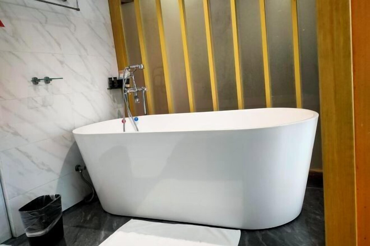 A modern bathroom with a freestanding bathtub, marble walls, and a black countertop.