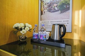 A reception desk with a vase of white flowers, two water bottles, and a coffee pot. - The Sussie Hotel (Quanzhou Fengze Yunlu) (Quanzhou)