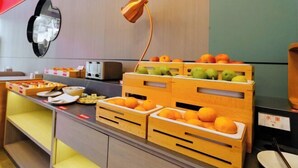 A breakfast bar with fruit and pastries, a modern lamp, and a mirror on the wall. - The Sussie Hotel (Quanzhou Fengze Yunlu) (Quanzhou)