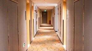 A hotel hallway with a patterned floor, doors on both sides, and a central walkway. - The Sussie Hotel (Quanzhou Fengze Yunlu) (Quanzhou)