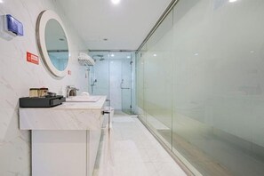 A modern bathroom with a marble vanity, a large mirror, and a glass shower enclosure.