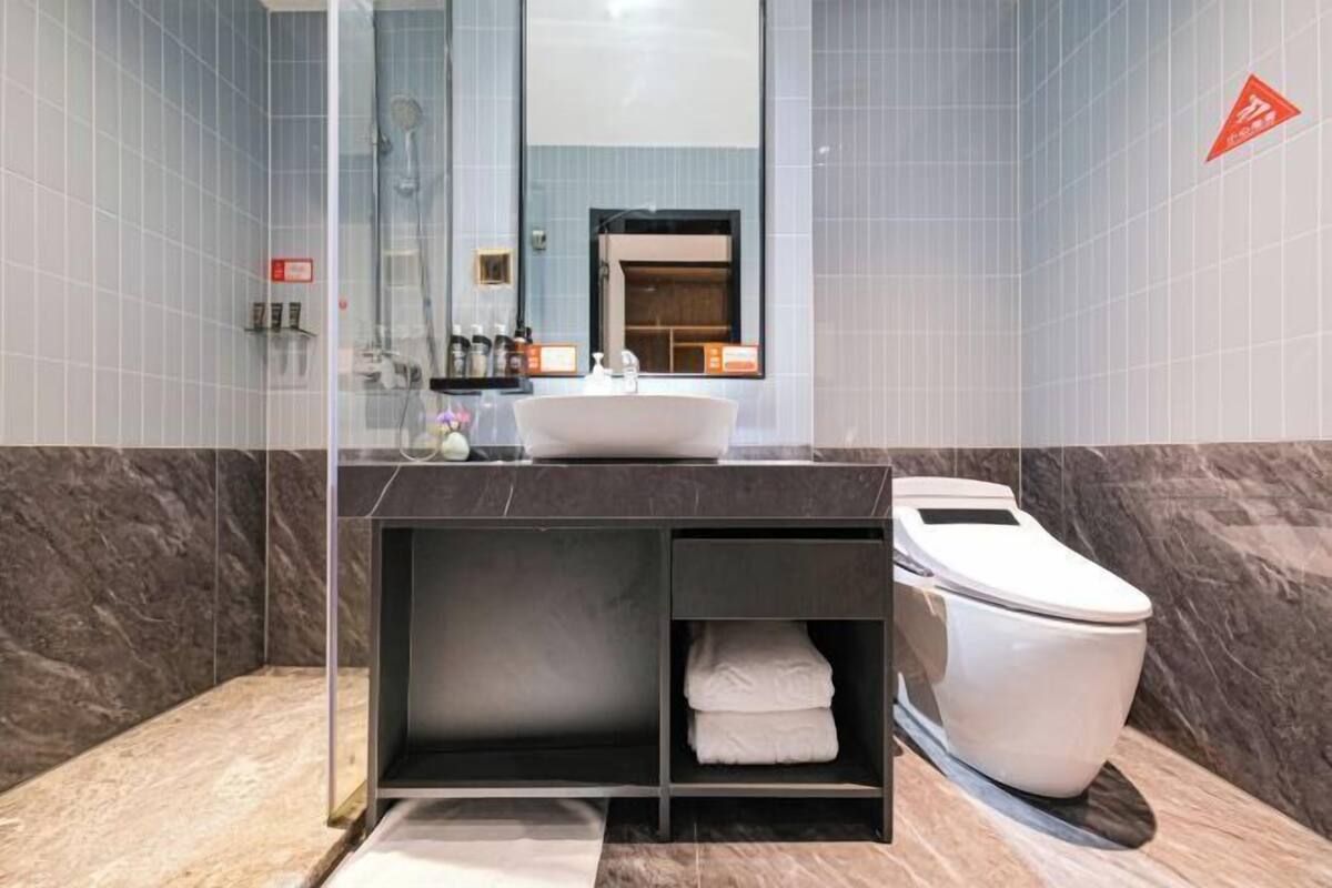 Une salle de bain moderne avec une douche à parois de verre, un lavabo blanc et des toilettes.