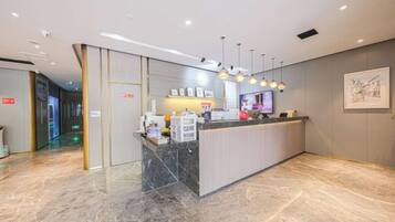 A hotel reception area with a marble floor, a reception desk, and a wall-mounted artwork.