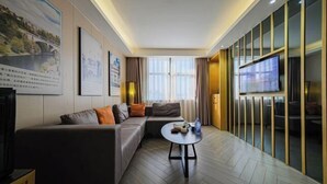 A modern hotel room with a sofa, a coffee table, a TV, and a large window with curtains. - The Sussie Hotel (Quanzhou Fengze Yunlu) (Quanzhou)