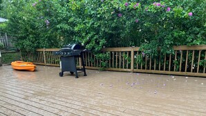 A wooden deck with a barbecue grill and a boat. - Cozy Chippewa Lake Ranch just steps from the lake! Kayaks and SUPs Private beach (Chippewa Lake)