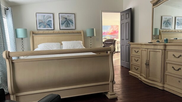 A bedroom with a large bed, a dresser, and two wall-mounted lamps. - Cozy Chippewa Lake Ranch just steps from the lake! Kayaks and SUPs Private beach (Chippewa Lake)