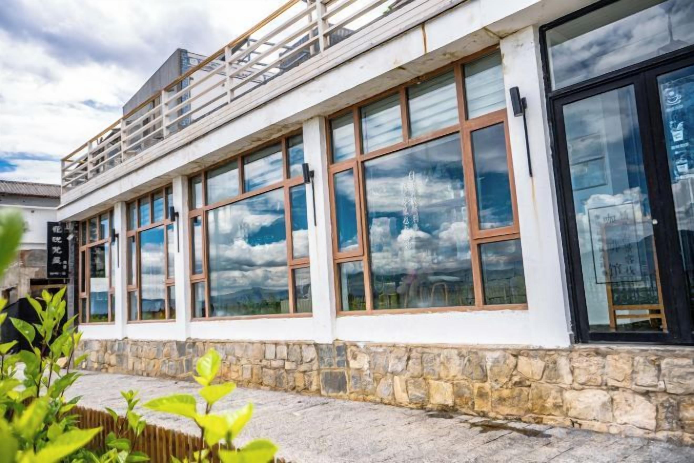 Un edificio con ampie finestre, pareti in pietra e ringhiera metallica al piano superiore.