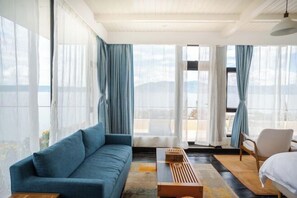 Una habitación de hotel moderna con sofá, una mesa de centro de madera, una silla y una cama.